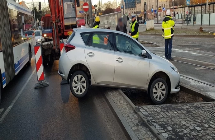 {Mieszkaniec Olsztyna przez nieuwagę zawisł na krawężniku przy tramwajowym torowisku.}